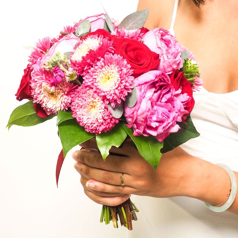 Gros plan sur le bouquet de mariée bordeaux, le bouquet est composé de rose parfumées et de reine-marguerite