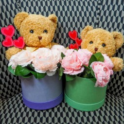 Duo d'oursons en peluche dans leurs chapeaux et roses artificiels